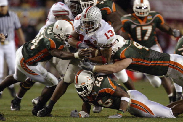 TEMPE, AZ - JANUARY 3:  Running back Maurice Clarett #13 of the Ohio State Buckeyes is gang tackled by the University of Miami Hurricanes defense during the Tostitos Fiesta Bowl at Sun Devil Stadium on January 3, 2003 in Tempe, Arizona.  Ohio State won th
