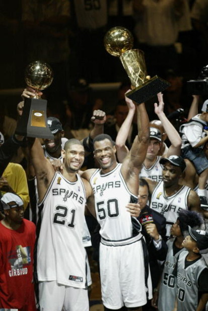 SAN ANTONIO - JUNE 15:  Tim Duncan #21 of the San Antonio Spurs holds up his NBA Finals MVP (Most Valuable Player) award as teammate David Robinson #50 holds up the 2003 NBA Championship trophy as the San Antonio Spurs celebrate in front of their fans aft
